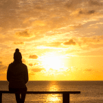 person staring at sunset over lake